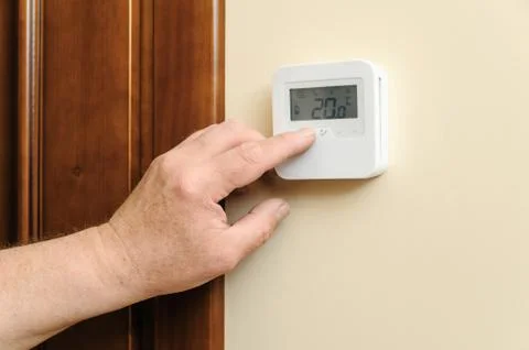 Man is changing  settings of a thermostat. Stock Photos