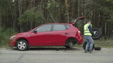 A man is changing a tire on a car on the roadside Stock Footage 221564096