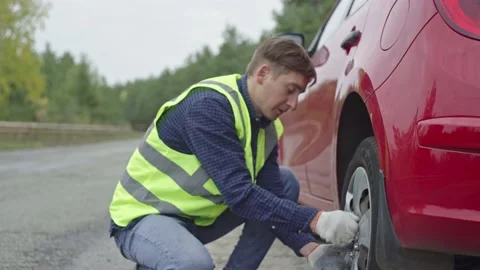 A man is changing a tire on a car on the roadside Stock Footage 221607062