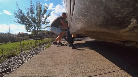Man changing wheel on trailer in yard Vídeo Stock 301696949
