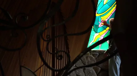 Man in chapel putting hands on stained glass window Stock Footage 67872491