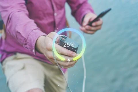 A man charges a Smartphone using a Power Bank with a 25 percent charge agains Stock Photos