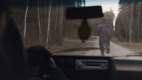 Man chased by a car through the forest road Stock Footage 83223605