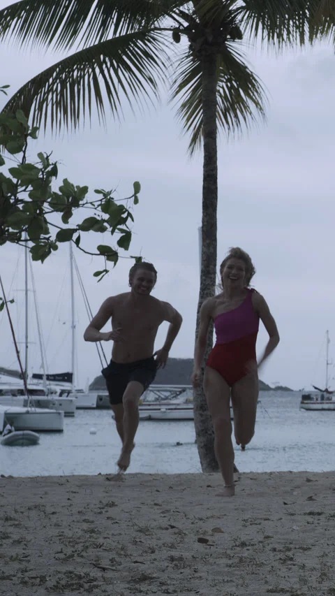 Man chasing and catching then kissing woman on beach  - vertical video / Salt Stock Footage 254624792