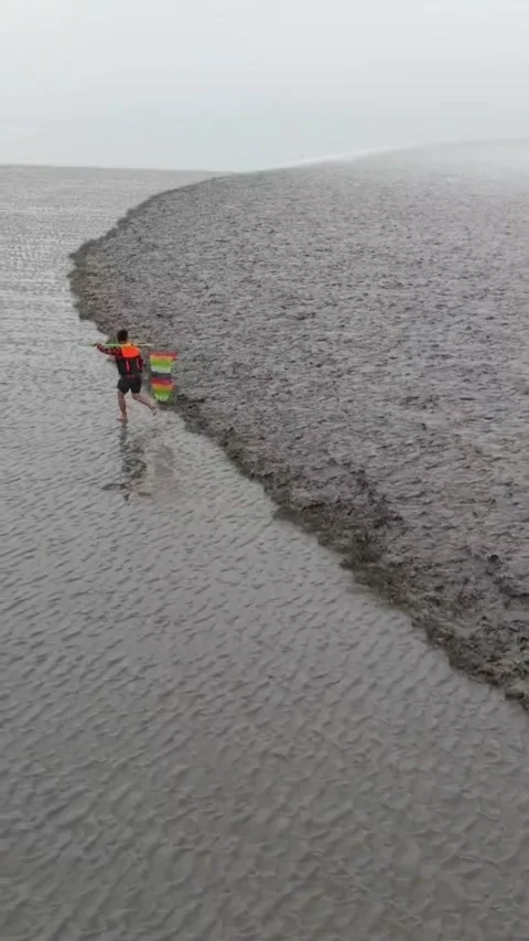 Man chasing Qiantang River tidal bore, a vibrant folk custom in Zhejiang, China Vídeos de archivo 337348014