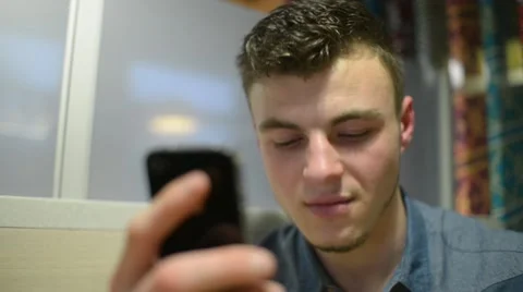 A Man chating with iphone Mobile Cell Phone drinking Coffee at table cafe Stock Footage 61011374