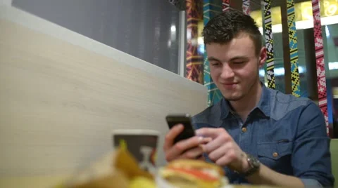 A Man chating with iphone Mobile Cell Phone at the Table Fast Food Cafe Stock Footage 61012144