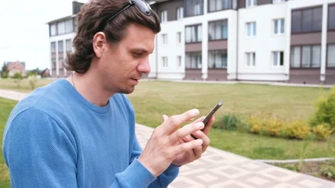 Man is chatting and typing message on mobile phone and sitting on the bench. Stock Footage 102451397