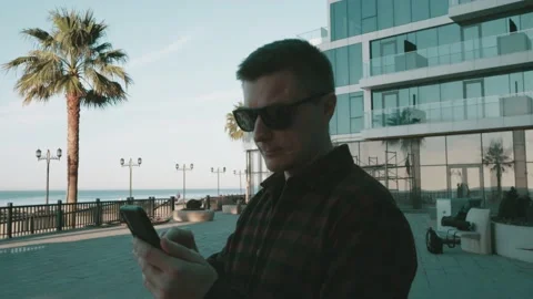 Man chatting on cell telephone standing in street. Young freelancer working at Stock Footage 230587764