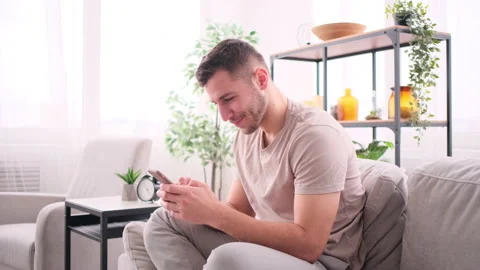 Man chatting on smartphone sitting on sofa 库存影片 171543577