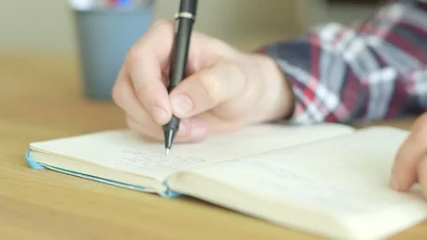 Man in a checked shirt writing a to do list in a notebook Stock Footage 79835466