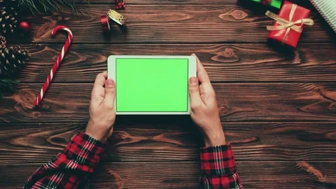 Man in checkered red shirt uses tablet on wooden table with Christmas Stock Footage 143563901