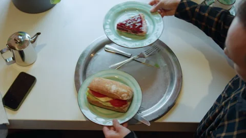 Man in checkered shirt reaches to remove sandwich pie plates from metal tray on 스톡 동영상 344875013