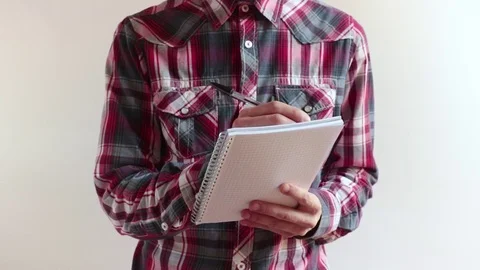 Man with checkered shirt takes notes Stock Footage 76794848