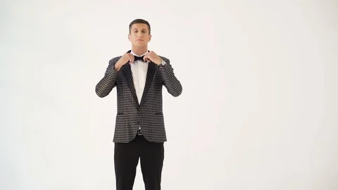 A man in a checkered suit with a bow-tie is parodying manners of macho Video stock 97786141
