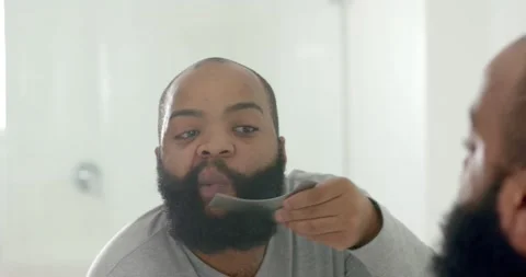 Man checking bathroom mirror, holding wide comb, combing beard and noting Stock Footage 336716485