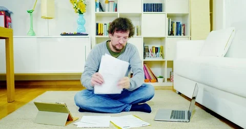 Man checking bills and taxes at home with tablet and pc Stock Footage 70869703