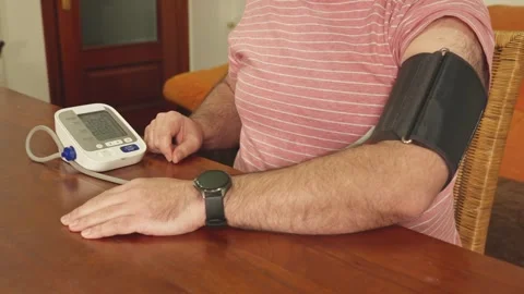 Man checking blood pressure at home using electronic monitor Stock Footage 327567785