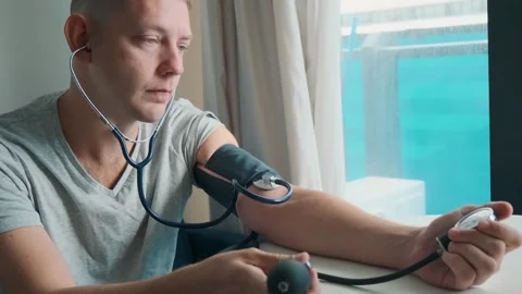 Man checking blood pressure manually with sphygmomanometer and stethoscope while Stock Footage 315861165