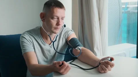 Man checking blood pressure manually with sphygmomanometer and stethoscope while Stock Footage 315861648