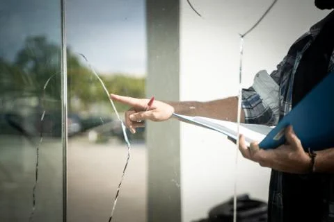 Man checking a broken glass from a house by the insurance company. Stock Photos