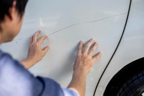 Man checking car scratch dent damage. Car care and protection concept. Stock Photos