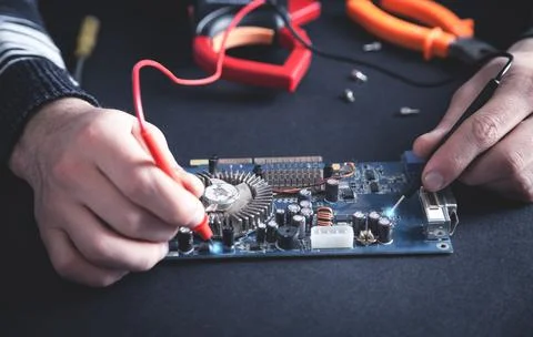 Man checking computer motherboard with a multimeter. Stock Photos