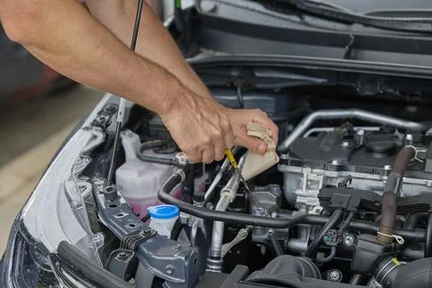 Man checking engine oil level in hybrid car during maintenance inspection Stock Photos