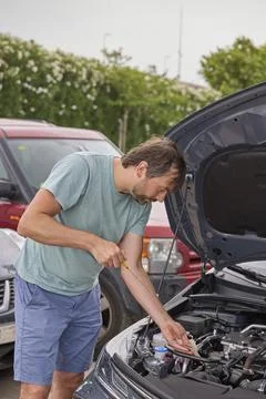 Man checking engine oil level in hybrid car during maintenance inspection Stock Photos