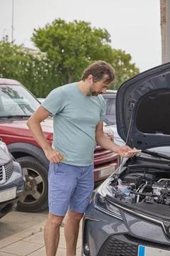 Man checking engine oil level in hybrid car during maintenance inspection Stock Photos