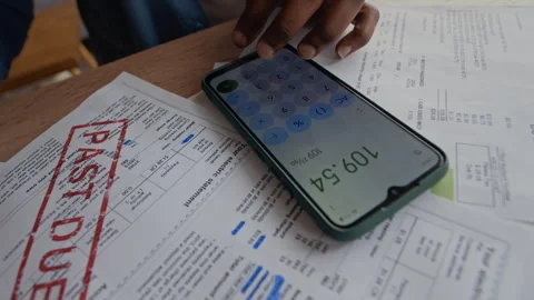 Man Checking Expenses on Smartphone Calculator While Managing Bills at Home Stock Footage 321866817