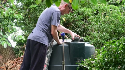 Man checking fuel level in domestic oil tank in garden uk Stock Footage 205470582