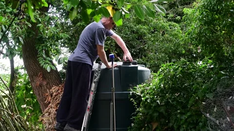 Man checking fuel level in domestic oil tank uk Stock Footage 205470625