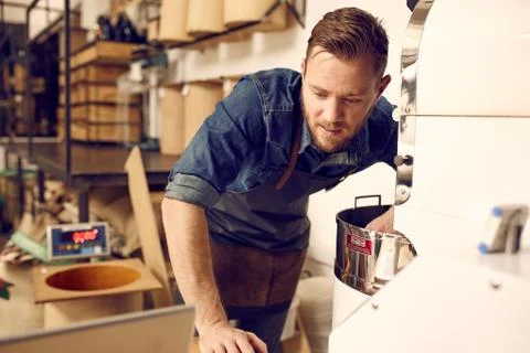 Man checking his laptop while operating a modern coffee roaster Stock Photos