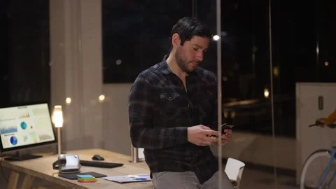 Man checking his mobile phone and smiling at camera at night Stock Footage 107628260