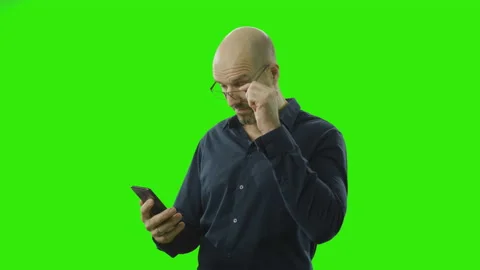 A man is checking his phone and starts laughing in front of a green screen Stock Footage 166512225