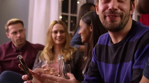 Man Checking Mobile Phone At Party With Friends Stock Footage 72518600