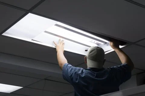 The man checking or changing Fluorescent light tube in the building. Stock Photos