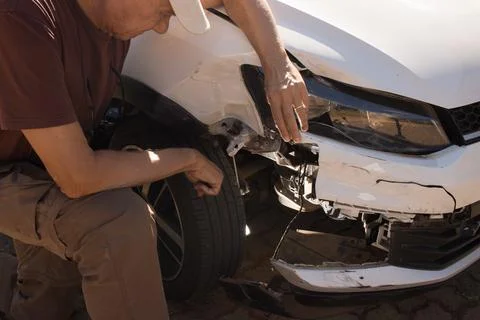 Man checking out the damage to the right front end bumper Stock Photos