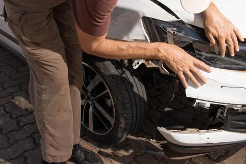 Man checking out the damage to the right front end bumper Stock Photos