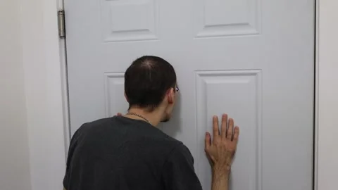 Man checking peephole with hands on door home security fear concept Stock Footage 331769592