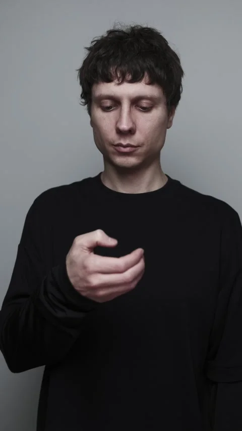 Man checking phone and scrolling distracted from work tasks on neutral grey Stock Footage 323715573