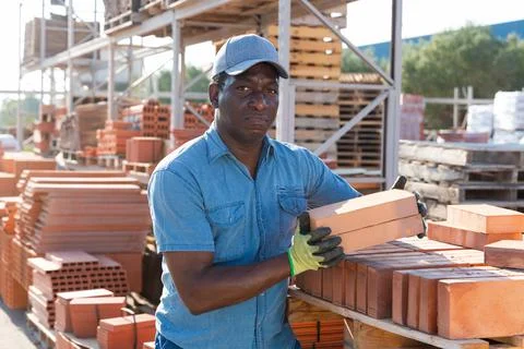 Man is checking quality of bricks in the open area of a construction store 스톡 사진