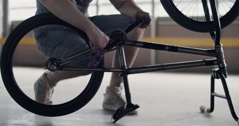 Man checking rear wheel of BMX bike Stock Footage 250050491
