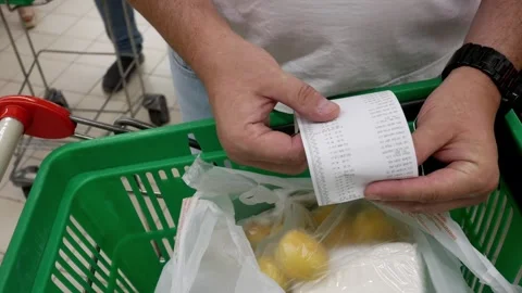 A man checking a receipt for paying for groceries in a store near the cash regis Stock Footage 279758222