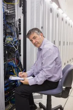 Man checking servers and writing on clipboard Stock Photos