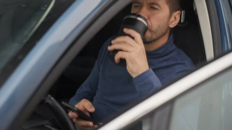 Man checking smartphone and drinking coffee in parked car Stock Footage 341846179