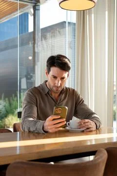 Man checking smartphone while drinking coffee at cafe Stock Photos