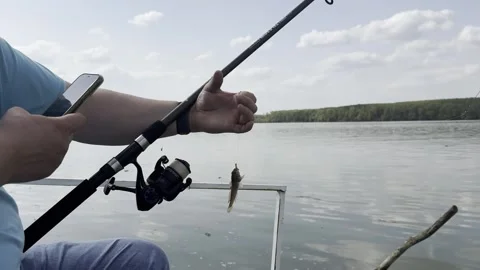 Man Checking Smartphone While Fishing on River, Modern Lifestyle and Leisure Con 動画素材 333922711