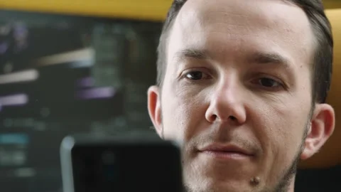 Man checking smartphone while working at dual-screen workstation Stock Footage 309313256